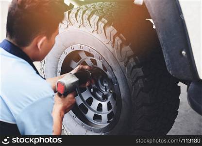 Repair or changing tire car pickup mechanic screwing unscrewing car wheel at repair service station automobile shop