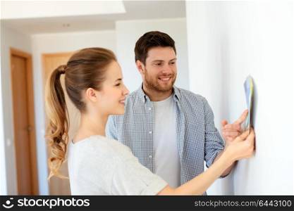 repair, people and interior design concept - happy couple with color samples palettes at new home. happy couple with color samples at new home