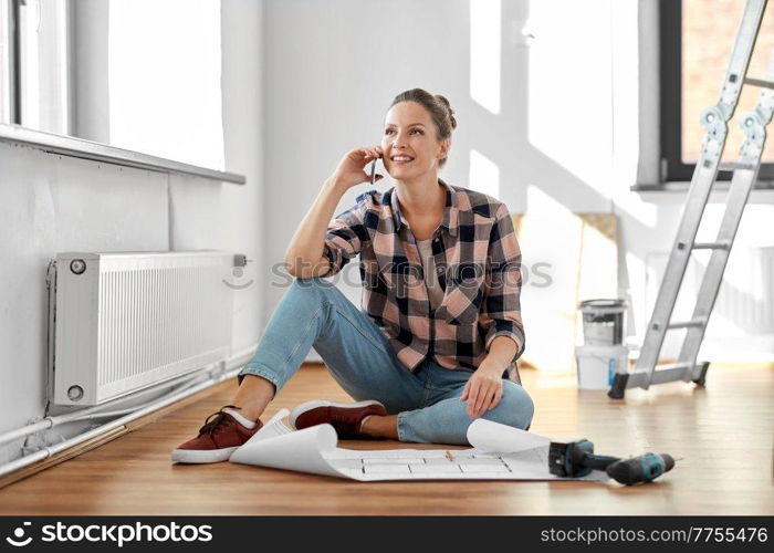 repair, people and real estate concept - happy smiling woman with blueprint and pencil sitting on floor at home and calling on smartphone. woman with blueprint calling on smartphone at home