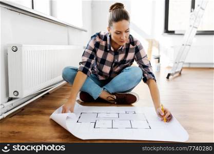 repair, people and real estate concept - woman with blueprint and pencil sitting on floor at home. woman with blueprint sitting on floor at home