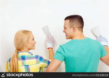repair, renovation and home concept - smiling couple doing renovations at home and looking at each other