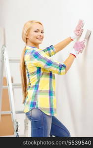 repair, renovation and home concept - smiling woman in gloves doing renovations at home