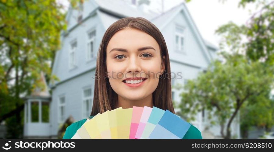 repair, renovation, decoration, design and people concept - smiling young woman with color swatches or samples over home background