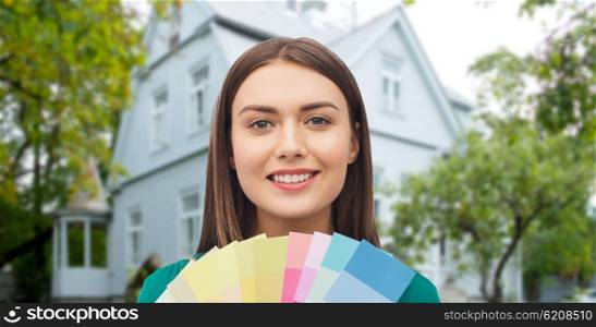repair, renovation, decoration, design and people concept - smiling young woman with color swatches or samples over home background