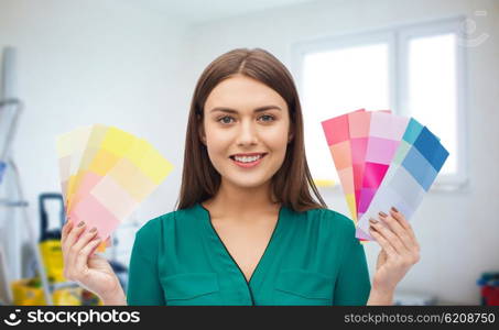 repair, renovation, decoration, design and people concept - smiling young woman with color swatches or samples over home background