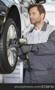 Repairman adjusting car&rsquo;s wheel in workshop