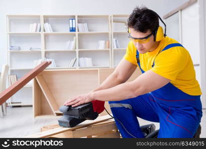 Repairman carpenter polishing a wooden board with an electric po. Repairman carpenter polishing a wooden board with an electric power polisher grinding wheel