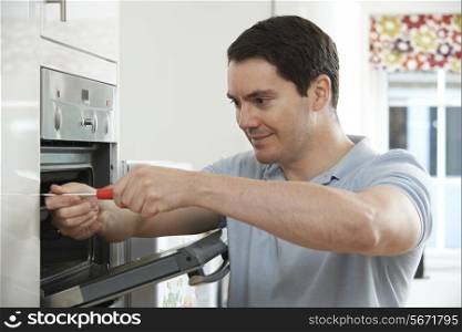 Repairman Fixing Domestic Oven In Kitchen