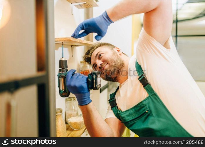 Repairman in uniform holds screwdriver, handyman. Professional worker makes repairs around the house, home repairing service