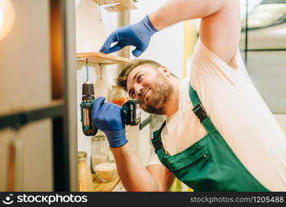 Repairman in uniform holds screwdriver, handyman. Professional worker makes repairs around the house, home repairing service