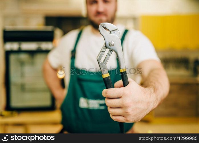Repairman in uniform holds wrench, handyman. Professional worker makes repairs around the house, home repairing service. Repairman in uniform holds wrench, handyman