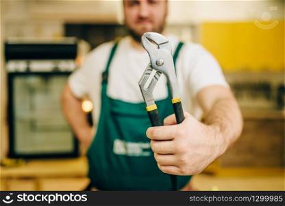 Repairman in uniform holds wrench, handyman. Professional worker makes repairs around the house, home repairing service. Repairman in uniform holds wrench, handyman