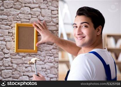 Repairman putting picture frame onto wall