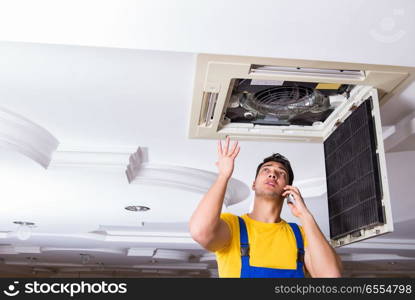 Repairman repairing ceiling air conditioning unit