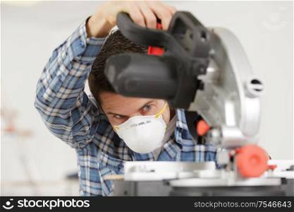 repairman standing with electric saw in mask