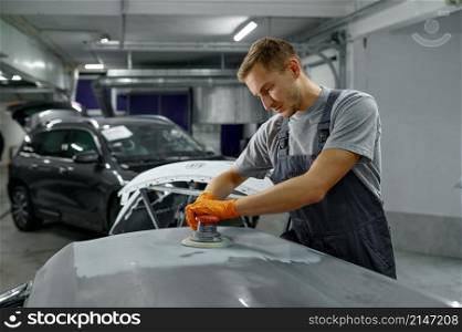 Repairman with sander abrasive materials removing old paint, rust from car body. Auto repair service. Repairman with sander removing old paint car