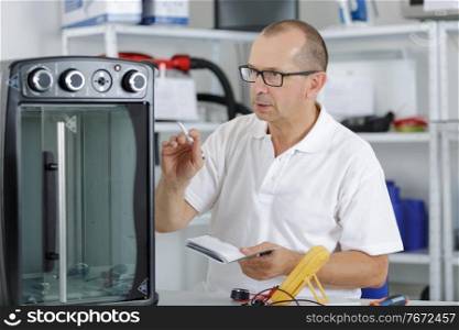repairman with screwdriver fixing oven in kitchen
