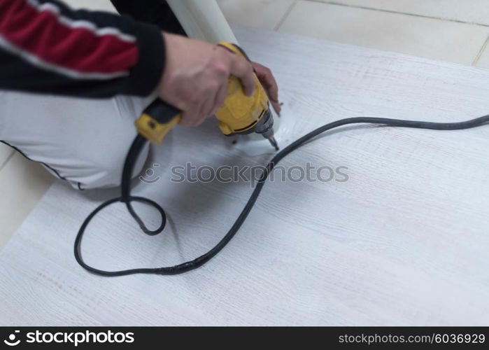 repairman working with drilling machine and assambling furniture