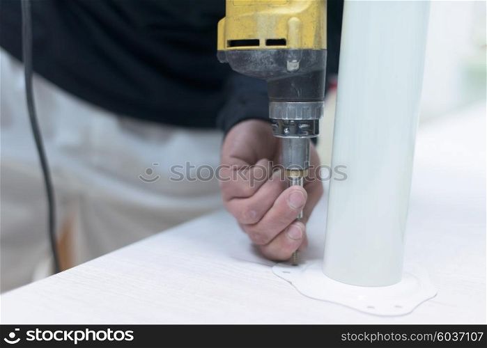 repairman working with drilling machine and assambling furniture