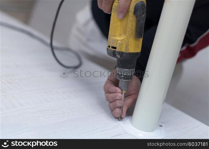 repairman working with drilling machine and assambling furniture