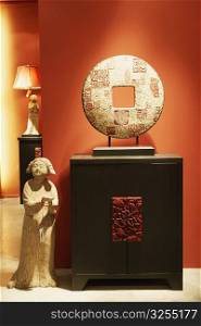 Replica of a traditional Chinese coin and a statue in a furniture store