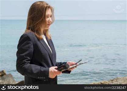 reporter holding notepad by sea