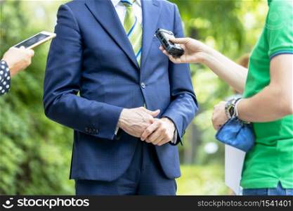 Reporter holding voice recorder making media interview with politician or business person