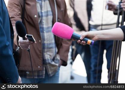 Reporters or journalists holding microphones, conducting television interview