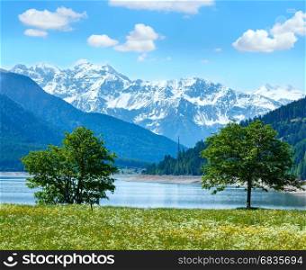 Reschensee ( or Lake Reschen) summer landscape with blossoming meadow and blue cloudy sky (Italy)