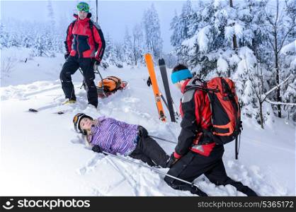 Rescue ski patrol help injured woman skier lying in snow