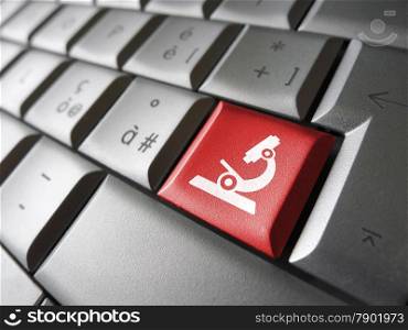 Research concept with microscope icon and symbol on a red laptop computer key for medical and online business.