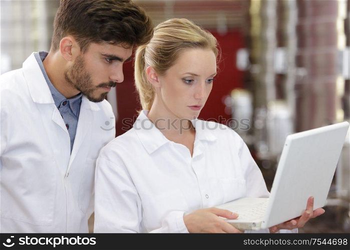 researchers in labcoats are checking the samples on laptop