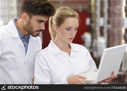 researchers in labcoats are checking the samples on laptop