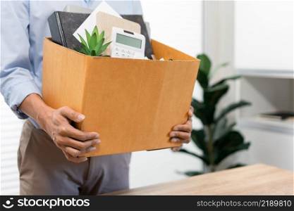Resignation Concept The male standing and using his hands lifting a box of his stuff.
