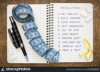 Resolutions written on a notepad with a measure tape and vitamin pills