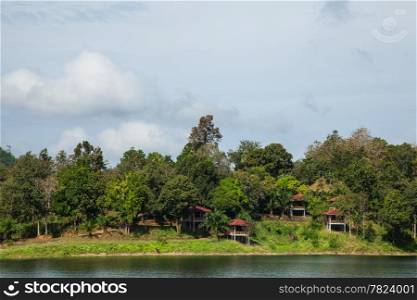 resort is next to the river. The resort is on a small hill surrounded by trees.