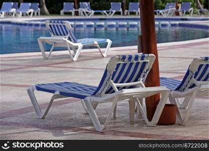 Resort pool lounge chairs sitting beside a large pool.. Resort Pool Lounge Chairs