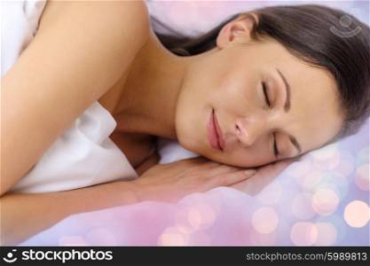 rest and comfort concept - beautiful woman sleeping in bed over lights background. beautiful woman sleeping in bed