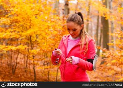 Rest and relax. Young attractive sporty girl with mobile phone smartphone on her arm with headphones listening music.. Sporty girl rest in forest listening music.