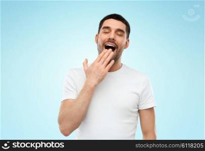 rest, bedtime and people concept - tired sleepy yawning man over blue background