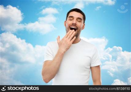 rest, bedtime and people concept - tired yawning man over blue sky and clouds background