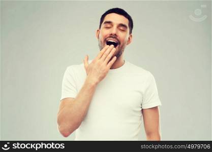 rest, bedtime and people concept - tired yawning man over gray background. yawning man over gray background