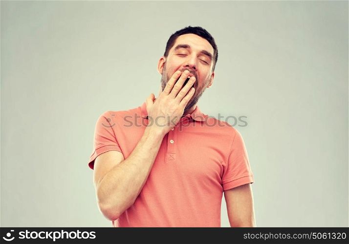 rest, bedtime and people concept - tired yawning man over gray background. yawning man over gray background