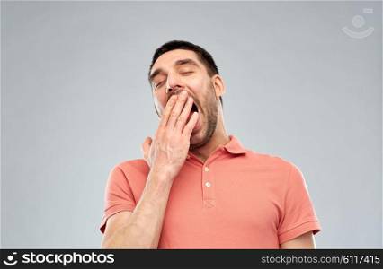 rest, bedtime and people concept - tired yawning man over gray background