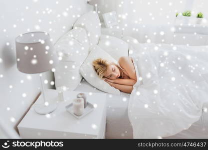 rest, comfort and people concept - young woman sleeping in bed at home bedroom over snow