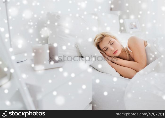 rest, comfort and people concept - young woman sleeping in bed at home bedroom over snow