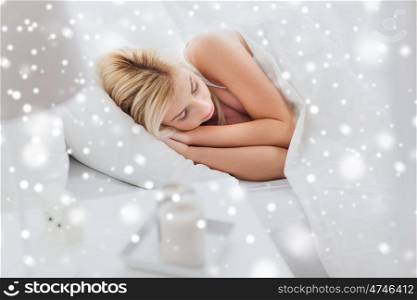 rest, comfort and people concept - young woman sleeping in bed at home over snow