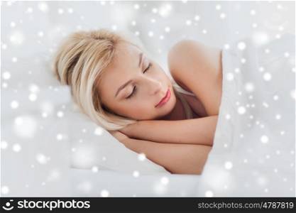 rest, comfort and people concept - young woman sleeping in bed at home over snow