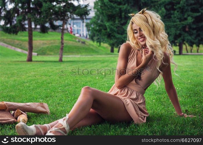 Rest in park, outdoor, people and leisure concept - beauty blonde alone young woman resting in the park. eauty blonde alone young woman resting in the park
