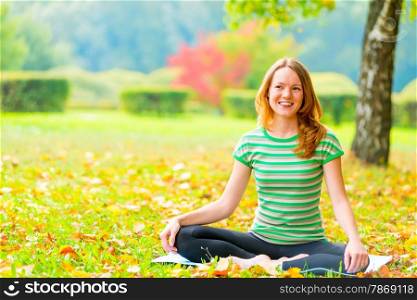 rest in the autumn park. woman practices yoga on the nature